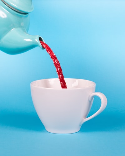 绿色茶壶倒红色液体白色茶杯特写摄影
